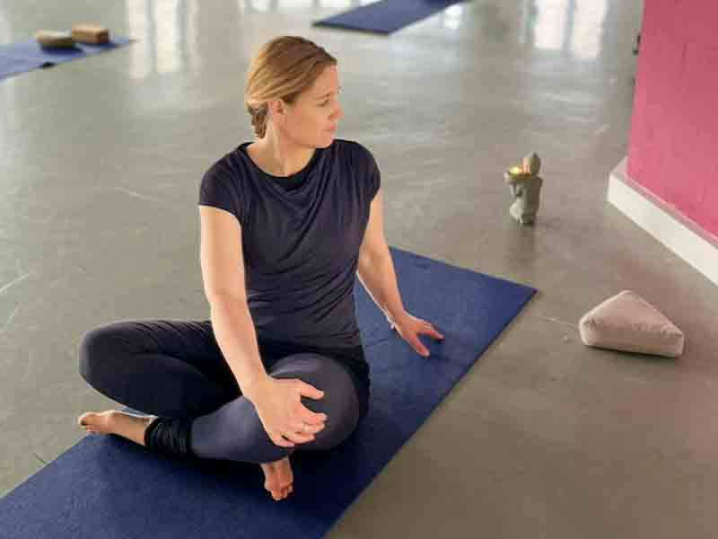 Frau sitzt im Schneidersitz auf einer Yogamatte in konzentrierter Haltung