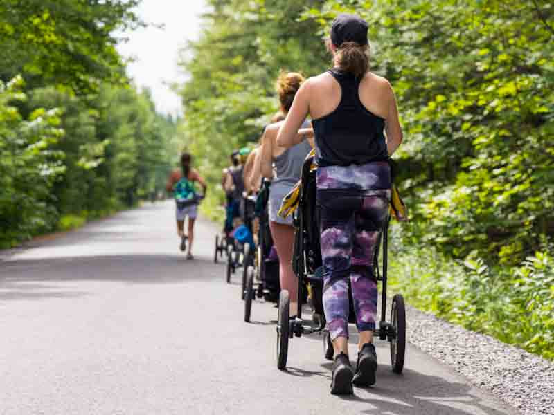 Gruppe von Frauen läuft mit Kinderwagen hintereinander