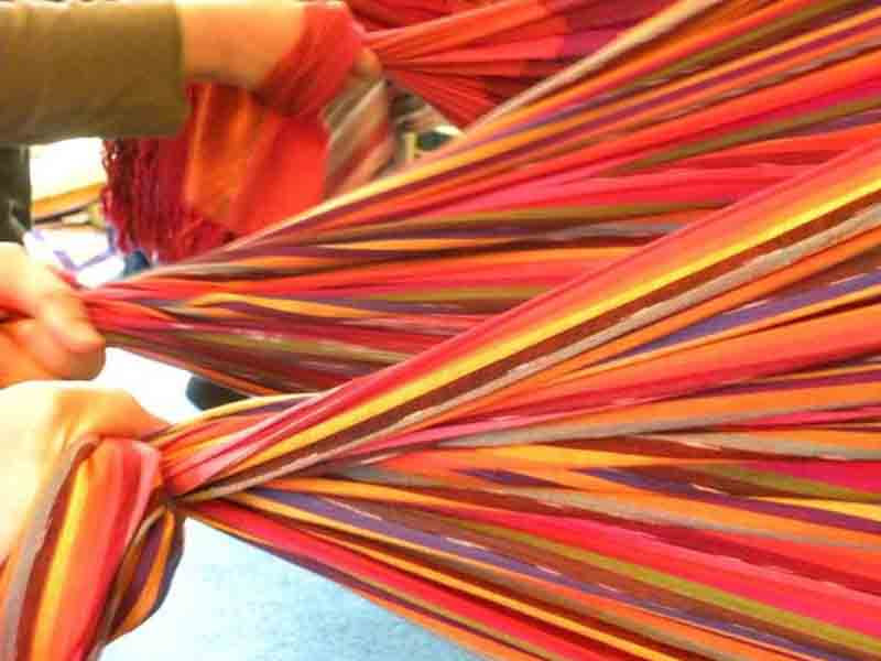 Rebozo massagetechnik; Bunte gestreifte Rebozo-Tücher werden mit den Händen straff gehalten