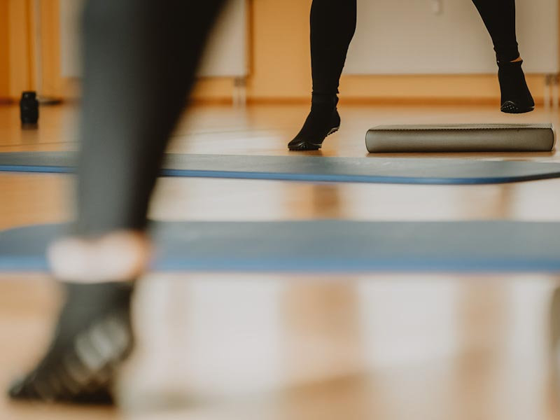 Beine von Teilnehmerinnen beim Stepptraining auf blauen Matten mit Stepbrett